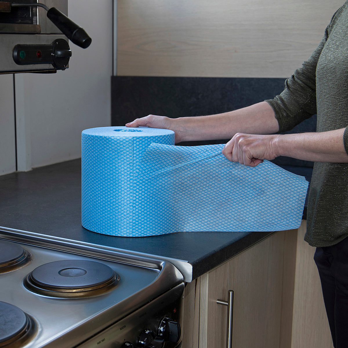 Person holding a large roll of blue Robert Scott handy wipe towels in a kitchen.